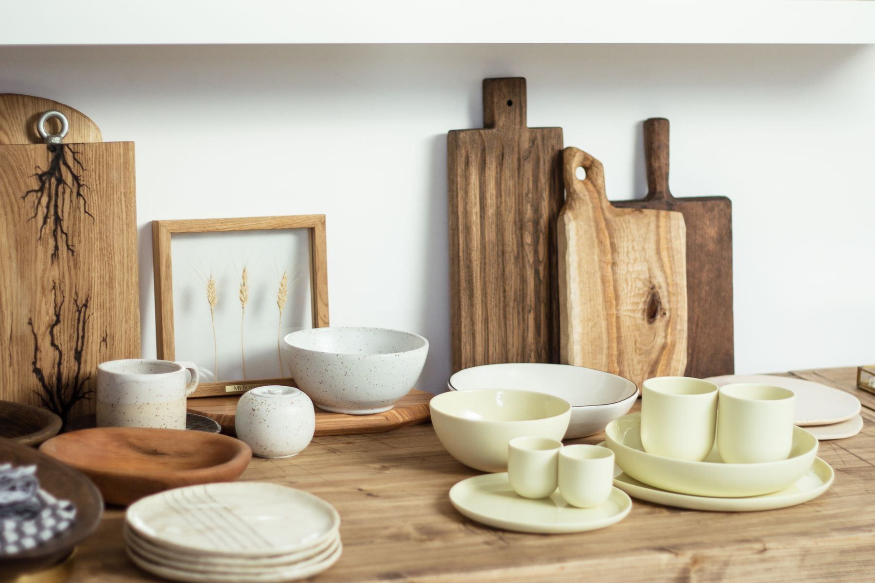 Mesa de madera con platos, tazas y cuencos de cerámica en tonos crema